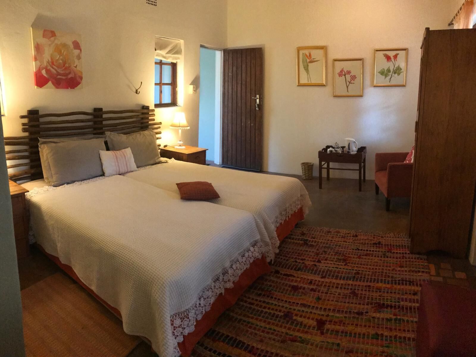 A bedroom with a bed, bedside tables, a chair, a small table, and framed pictures on the wall.