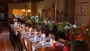 A restaurant with long tables set for dining, candles, and floral centerpieces. - Old Joe's Kaia (Mbombela)