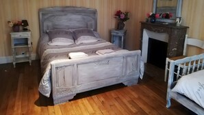 Un dormitorio con cama, mesita de noche, cómoda, espejo y una silla.