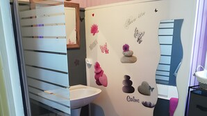 Un baño con lavamanos, espejo, toallero y una pared decorativa con pegatinas de corazones y flores.