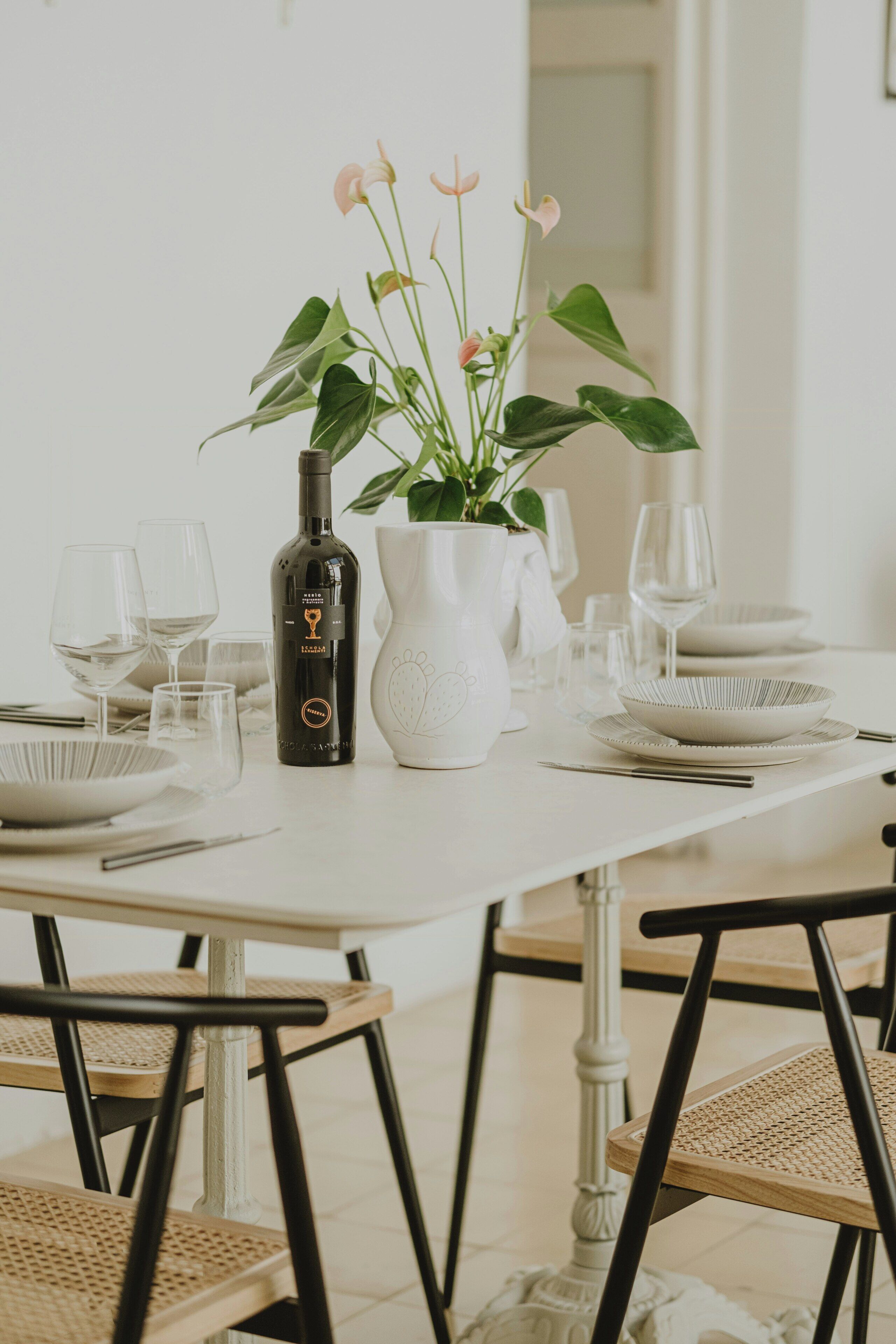 A dining table set with wine glasses, plates, and a bottle of wine.
