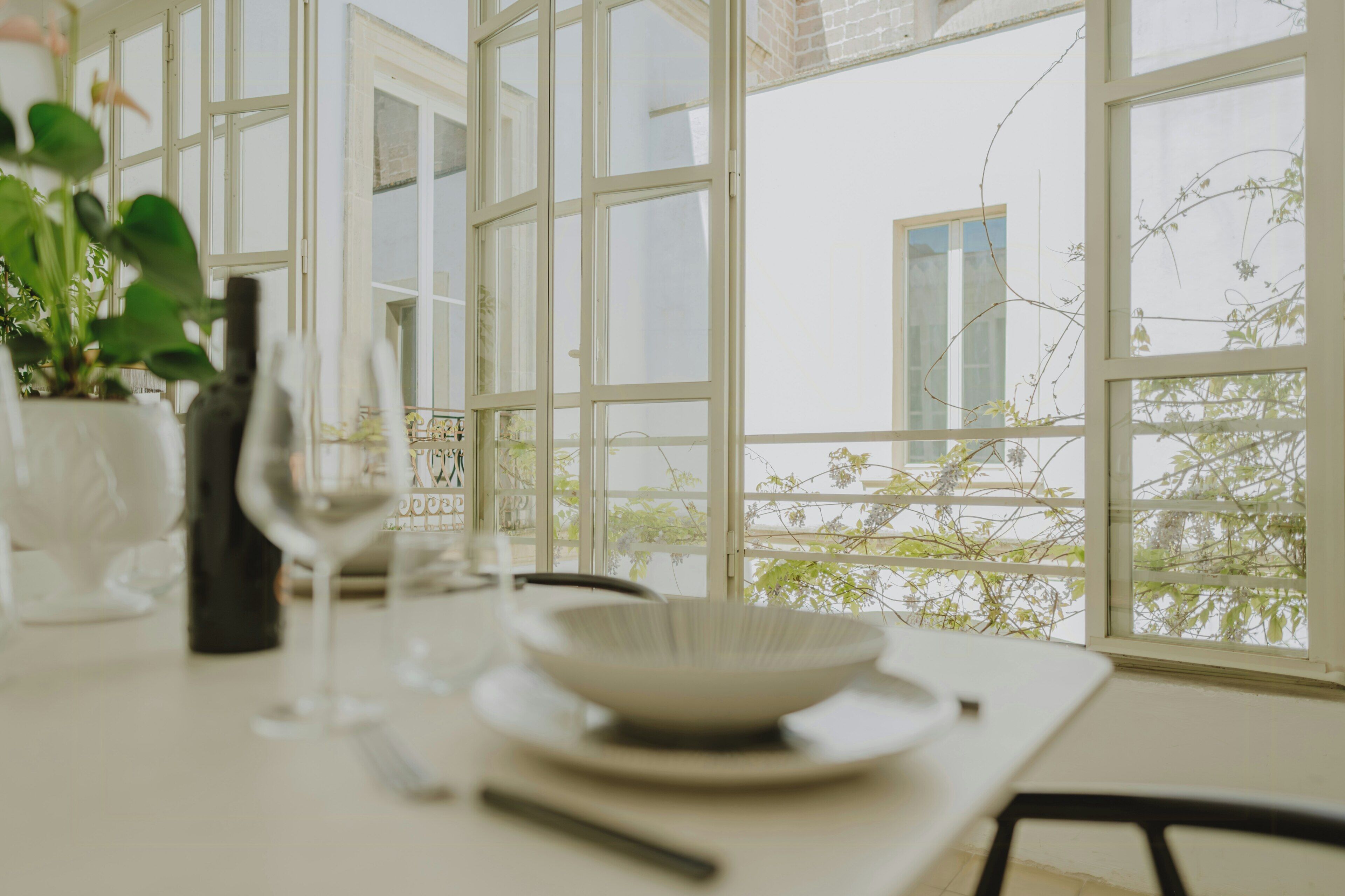 Ein Esstisch mit Schüssel und Weinglas, große Fenster und Blick ins Grüne.