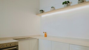 Een keuken met witte kastjes, een inbouwoven en een aanrecht.