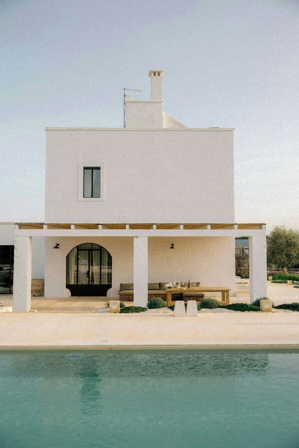 A modern two-story house with a pool, a covered patio, and a large arched doorway. - Farmhouse with pool in olive grove near Ostuni (Ostuni)