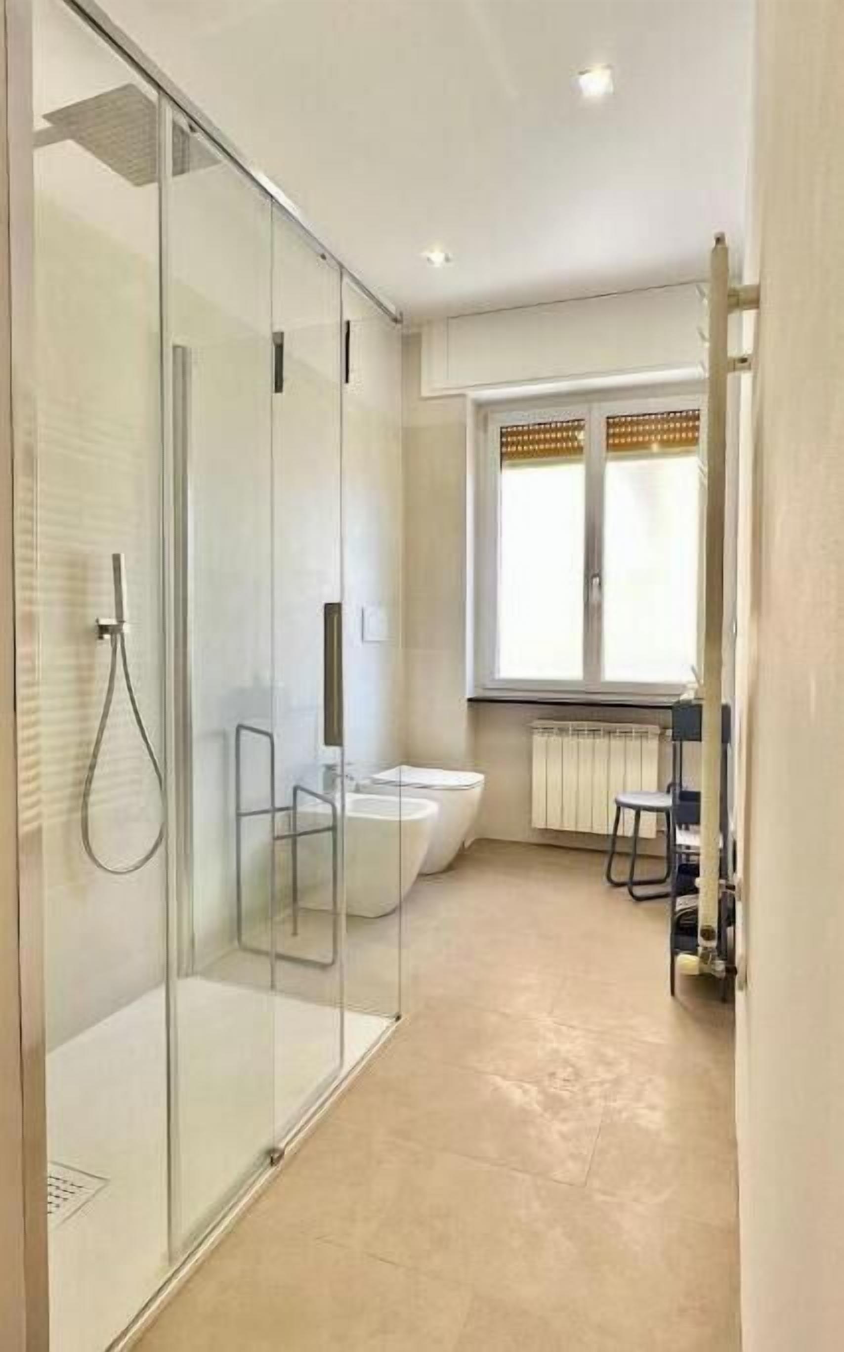 Une salle de bain moderne avec une douche à l’italienne, une baignoire blanche et des toilettes.