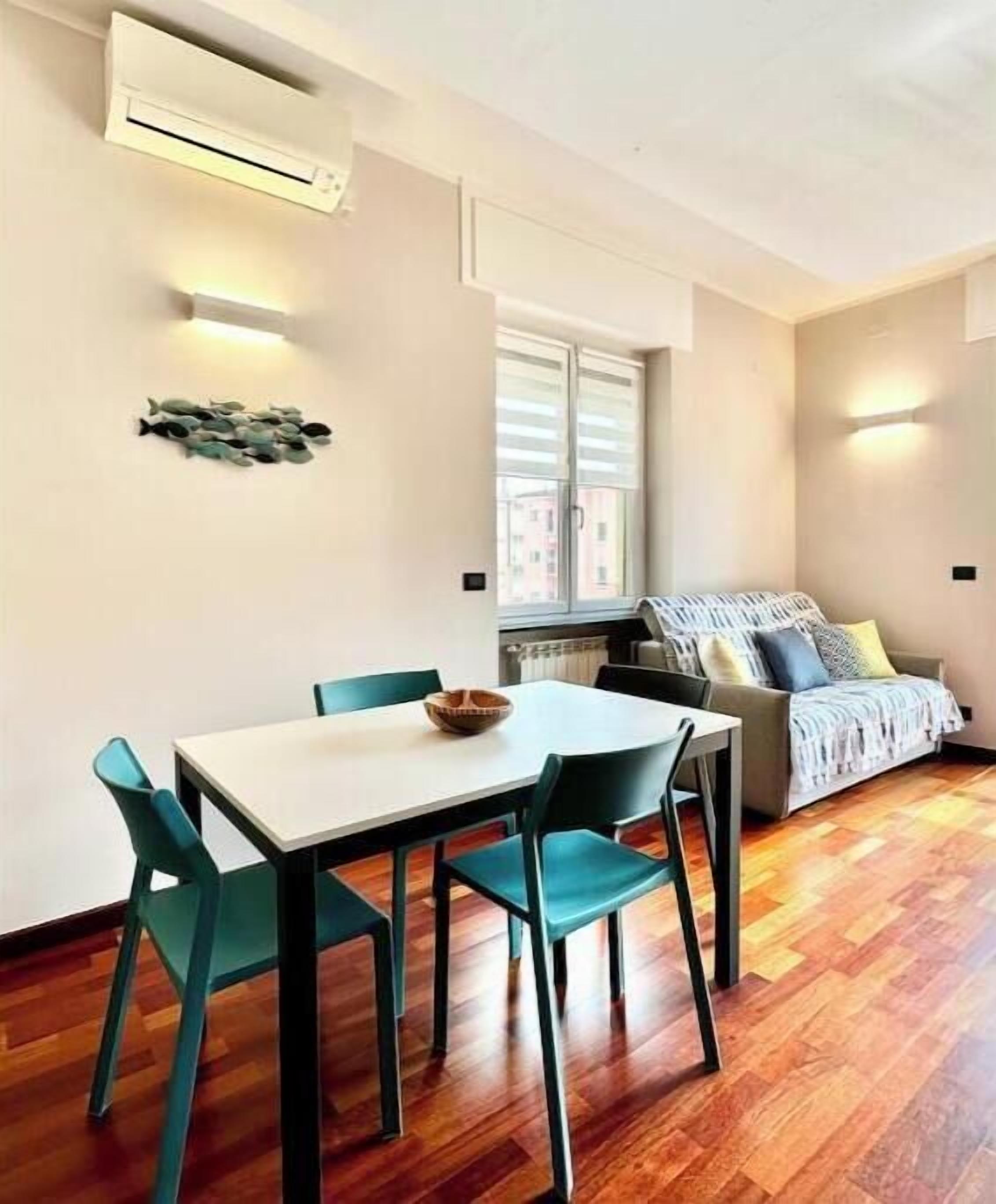 A compact living space with a dining table, chairs, a sofa, and a window.