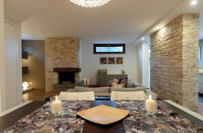 A dining area with a table set for two, a fireplace, and a stone accent wall.