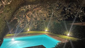A swimming pool surrounded by stone pathways and greenery, with ambient lighting. - Villa with pool at Lake Bracciano (Bracciano)