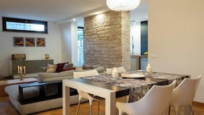 A modern living room with a dining area, stone accent wall, and a chandelier. - Villa with pool at Lake Bracciano (Bracciano)