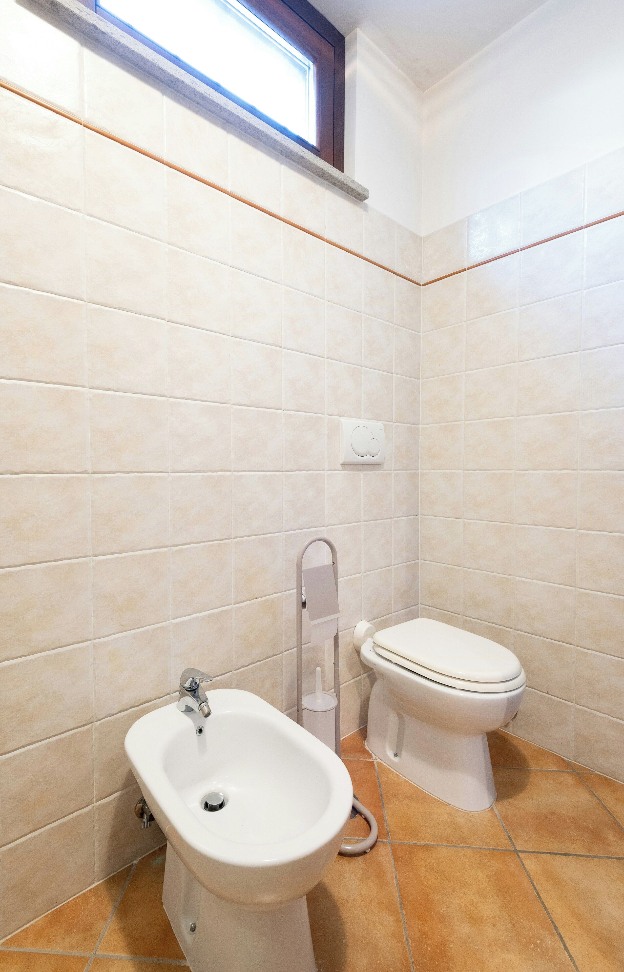 Et badeværelse med bidét, toilet og et vindue.