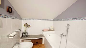 A bathroom with a bathtub, a sink, a vanity, and a shower.