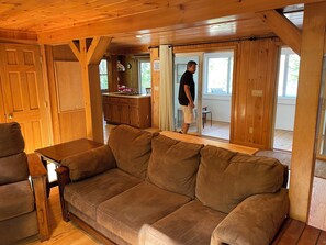 A wooden interior with a sofa, a table, and a kitchen area.