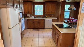 A kitchen with wooden cabinets, a refrigerator, a dishwasher, a sink, and a window.