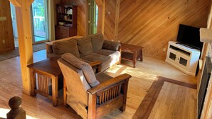 A wooden interior with a sofa, a small table, a television, and a bookshelf.