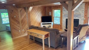 A wooden-paneled room with a sofa, a TV, and a fireplace.