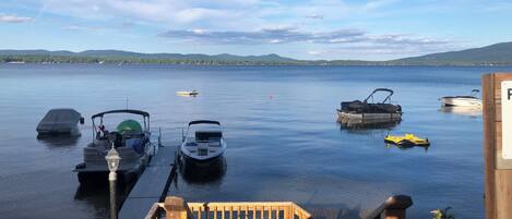 A wooden dock leading to a calm lake with several boats docked.