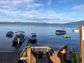 Un muelle de madera que conduce a un lago tranquilo con varias embarcaciones amarradas.