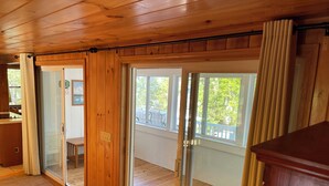 A room with wooden flooring, a sliding glass door leading to an outdoor area, and a view of the outdoors.