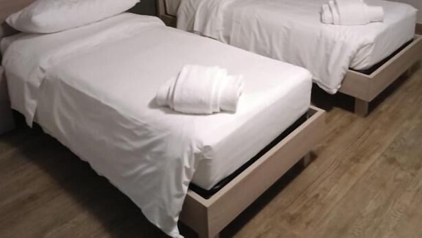 Two single beds with wooden headboards, white bedding, and a wooden floor. - osteria il becco fine affittacamere (Cumignano sul Naviglio)