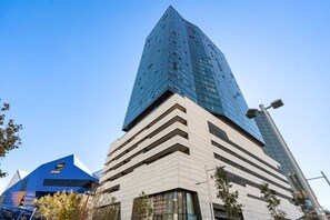 A modern building with a prominent glass facade and a unique architectural design. - City Sky Nest - Luxe Apartment with City Views (Perth)