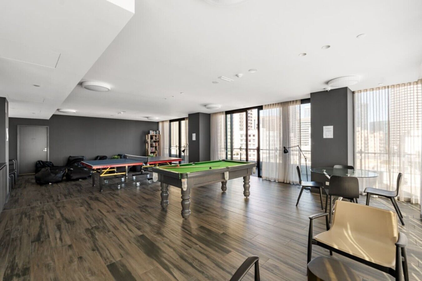 A modern indoor recreational area with a pool table, ping pong table, and seating area.