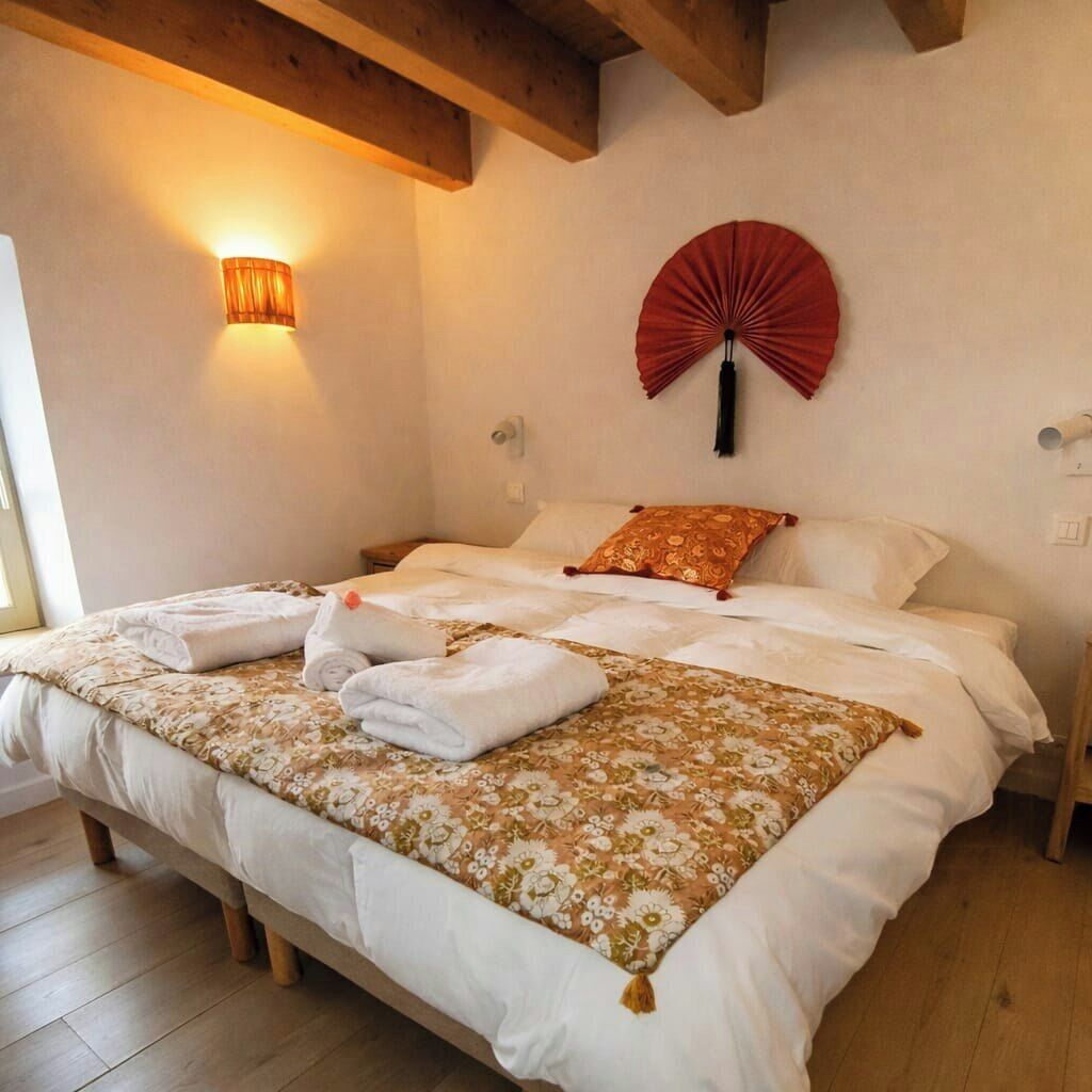 Een slaapkamer met een bed, een ventilator aan de muur en een bedlampje.