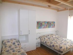 Ein Schlafzimmer mit zwei Betten, einem Kleiderschrank, einem Nachttisch und einem farbenfrohen, abstrakten Gemälde an der Wand.