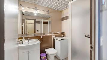 Une salle de bain moderne équipée d’un lavabo, d’un miroir, de toilettes et d’un lave-linge.
