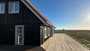 Ein großes Holzhaus mit geneigtem Dach und einer Holzterrasse.