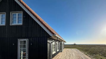 Un grand bâtiment en bois, doté d’un toit en pente et d’une terrasse en bois.
