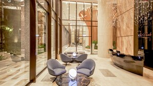 Eine moderne Lobby mit Glaswänden, einer Rezeption und Sitzbereichen.