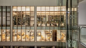 Ein mehrgeschossiges Gebäude mit Glasfassade, Fitnessraum und Sitzbereichen.