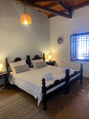 Une chambre à coucher avec un lit à baldaquin, deux lampes de chevet, un tapis à motifs et une fenêtre avec des barreaux.