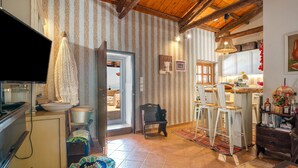 A cozy kitchen with a wooden ceiling, a television, and a dining area with stools. - Peloponnese Beachfront Villa (Gelinas Beach house) (Paralia)