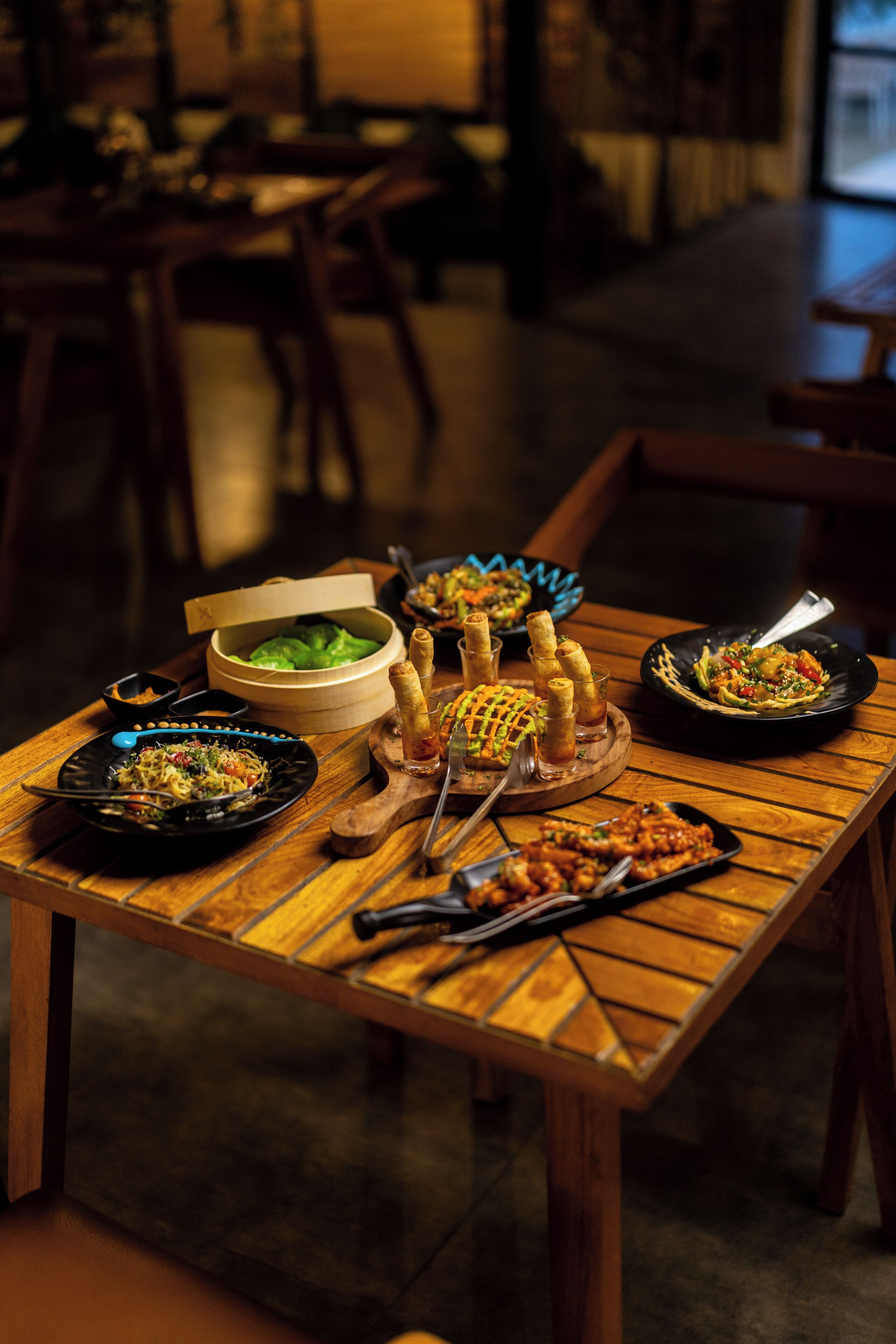 A dining table with various dishes, a bowl of green salad, and a wooden table.