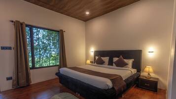 Un dormitorio con un ventanal grande, una cama con cabecera, lámparas de noche y suelo de madera.