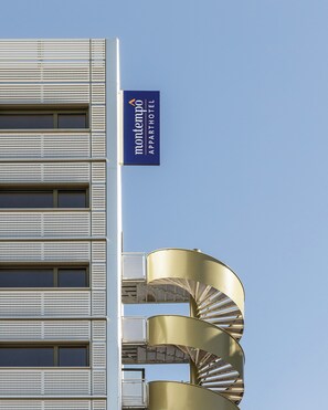 A building with a sign reading 'montempex aparthotel' and a spiral staircase.