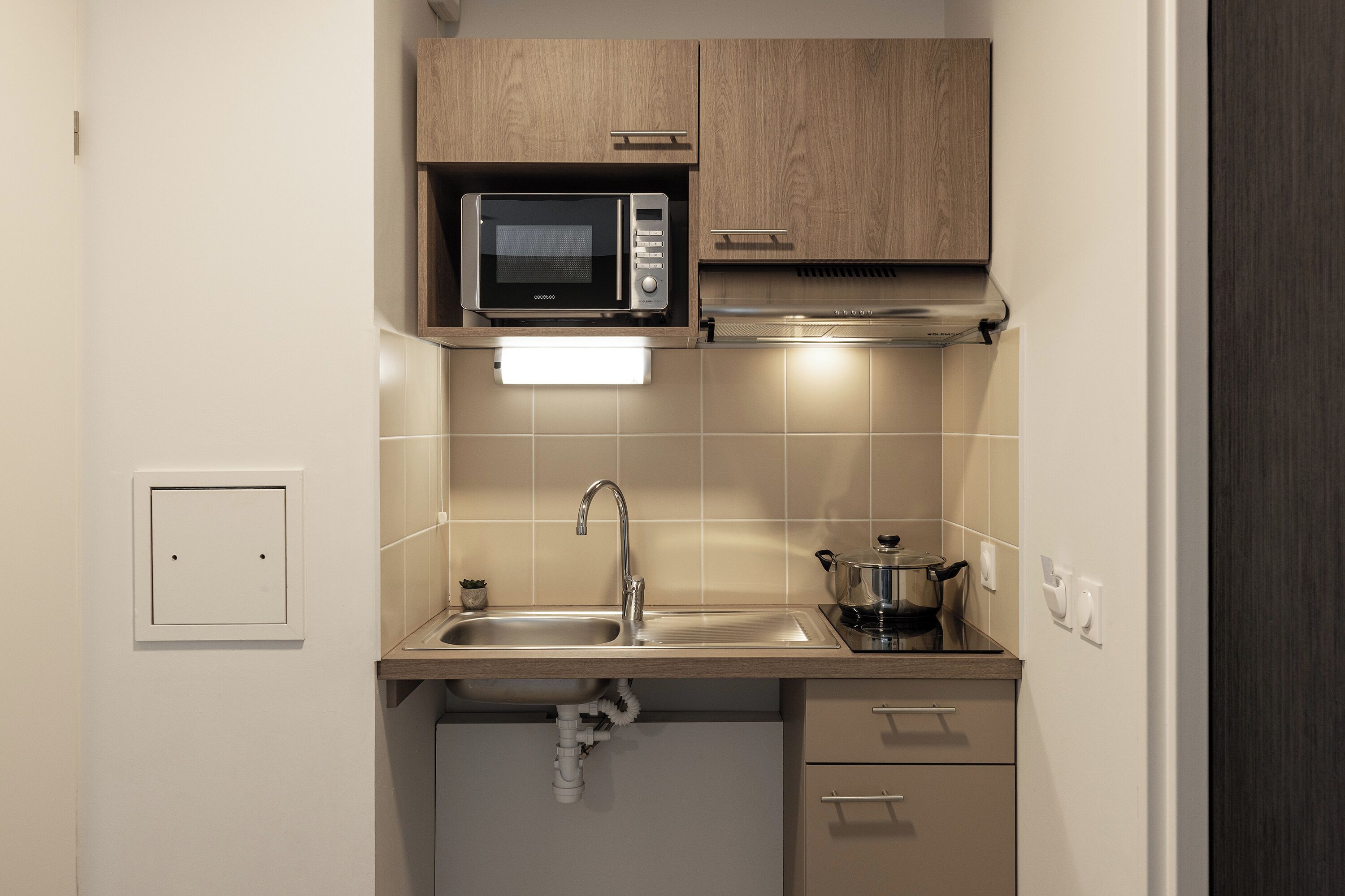A compact kitchen with a microwave, sink, and cabinets.
