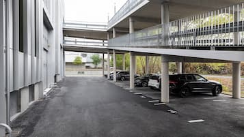 A parking area with multiple cars, a building with a sign, and a pedestrian bridge.