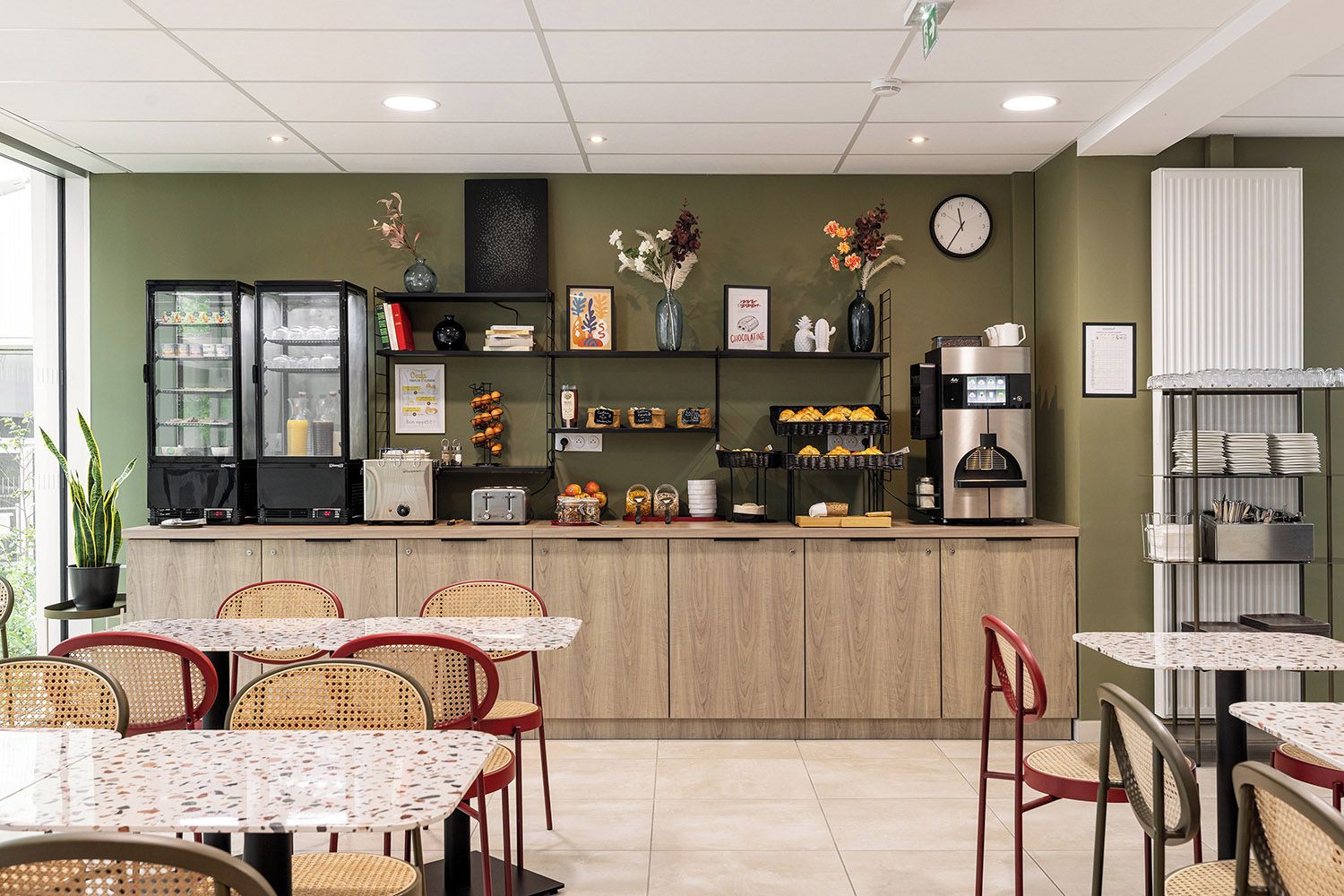 A cafe with a wooden counter, various food items, and a clock on the wall.