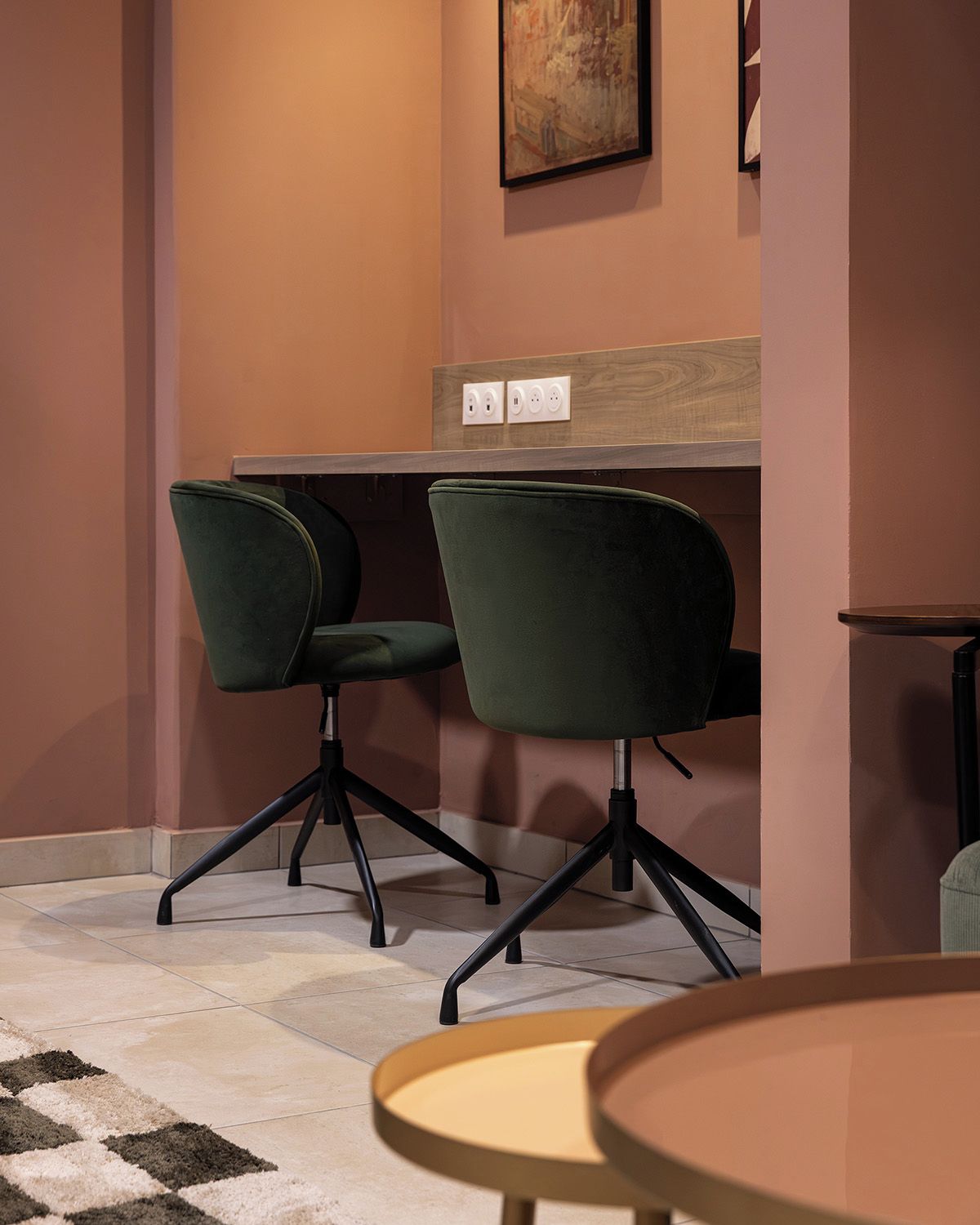 A conference room with two green chairs, a wooden table, and a painting on the wall.