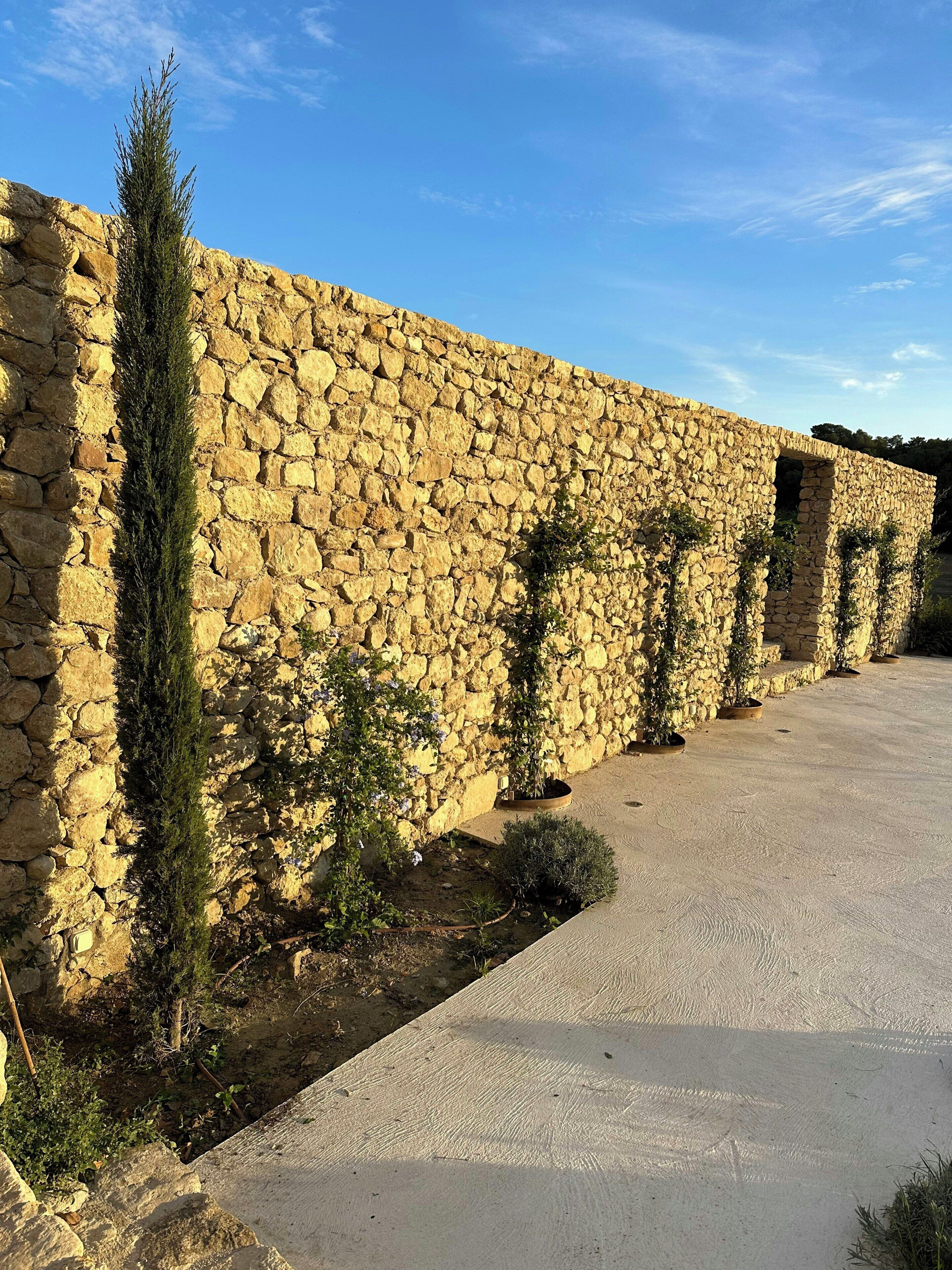 A stone wall with a pathway leading to a building entrance.
