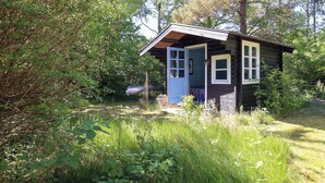 A small cabin with a blue door, surrounded by dense greenery. - Cottage with forest idyll and peace by Arresø (Frederiksværk)