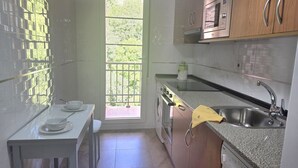 Une cuisine compacte équipée d’un lave-linge, d’un four à micro-ondes et d’un évier.