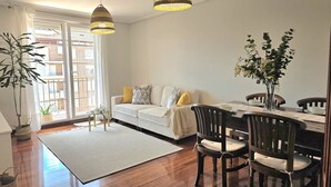 Un salon comprenant un canapé, une table à manger, des chaises et des lampes suspendues.
