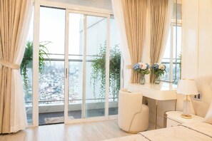 Quarto moderno com uma grande porta de vidro deslizante, uma toucador branco com espelho e uma mesa de cabeceira com abajur.