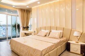 Un dormitorio moderno con una cama grande, mesitas de noche y vistas a la ciudad.