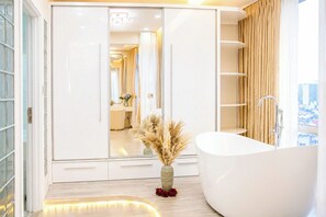 A modern bathroom with a freestanding bathtub, a vanity with a mirror, and a large mirror reflecting the room. - The Crown Luxury 4BR Penthouse (Ho Chi Minh City)