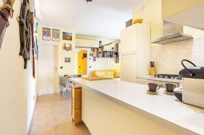 A modern kitchen with a central island, a stove, and a coffee machine. - Hostdomus - Apnea House (Finale Ligure)