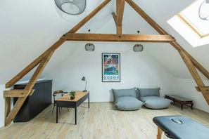 Un cuarto tipo loft con vigas de madera expuestas, un escritorio con silla, una cama con almohadas y un cartel en la pared.